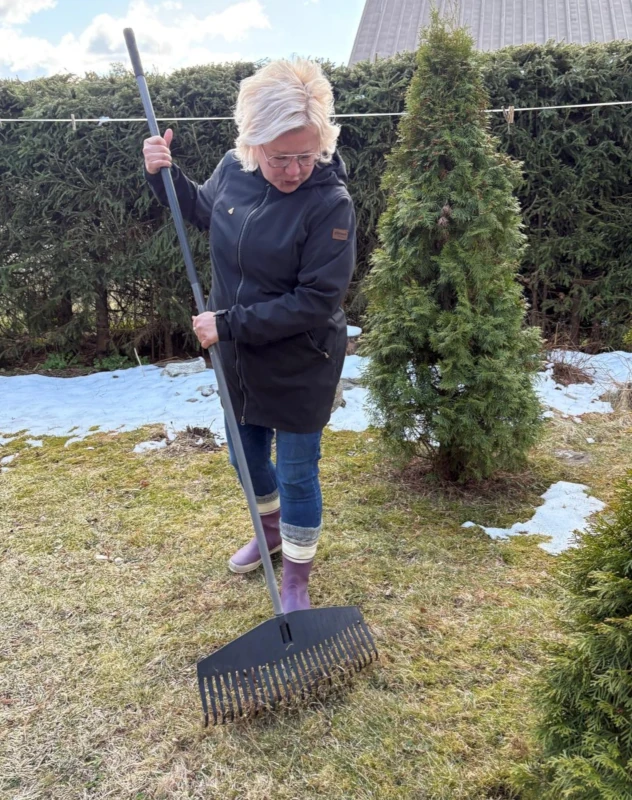 Sanna haravoi lehtiä Kotiavun asiakkaan takapihalla.